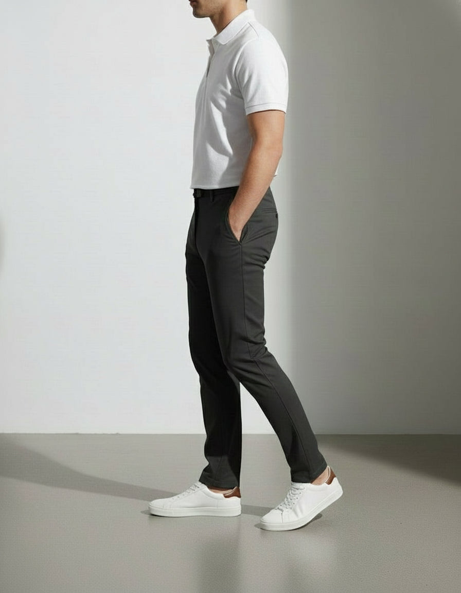 Person wearing a white polo shirt, dark pants, and white sneakers on a plain background