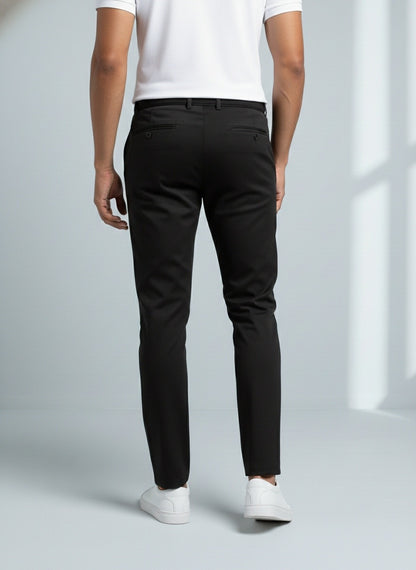 Person wearing black pants and white shoes on a light gray background