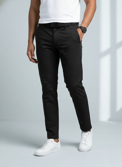 Person wearing black pants and white sneakers on a light gray background