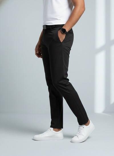 Person wearing black pants and white sneakers on a light gray background