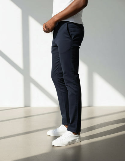 Person wearing navy pants and white sneakers standing in a well-lit room with shadows on the floor.