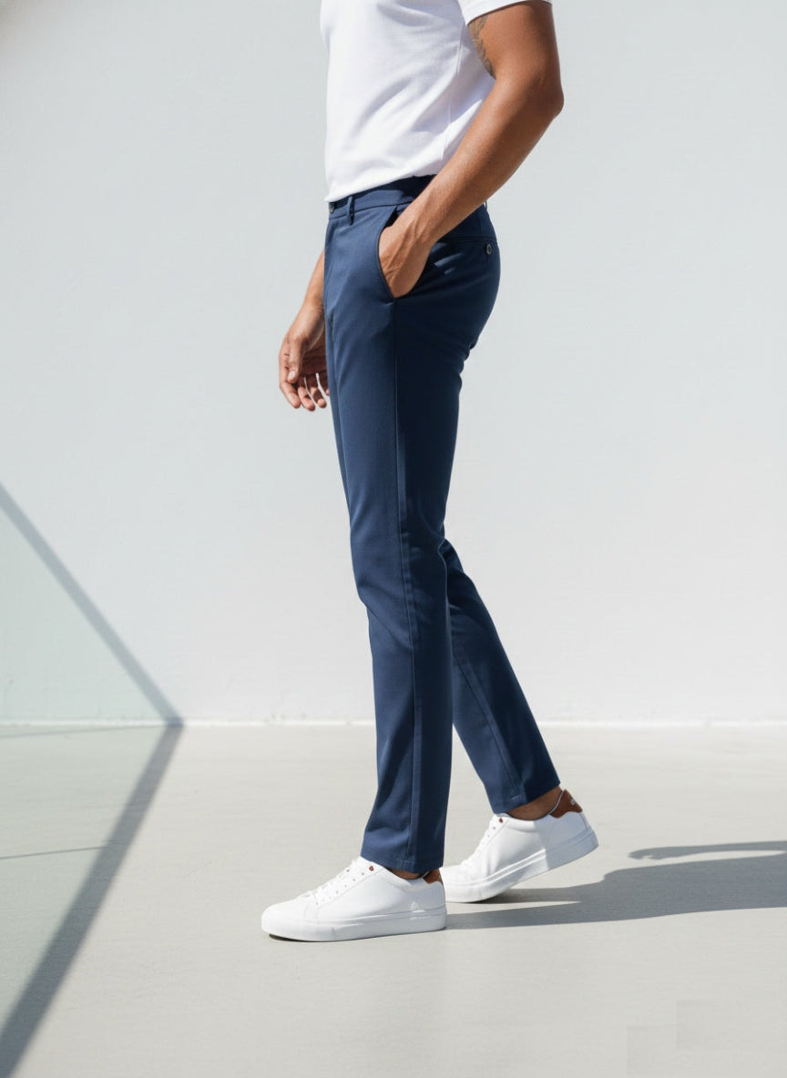 Person wearing navy pants and white sneakers on a light gray background 