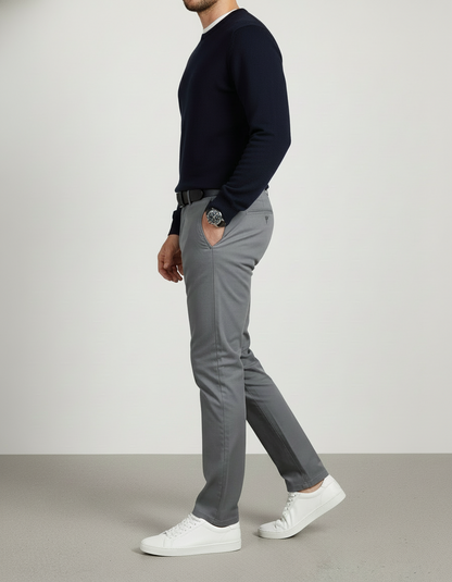 Person wearing a navy sweater, gray pants, and white shoes on a plain background